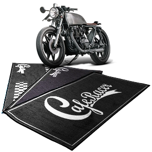 Moto Cafe Racer su tappeti neri con scritte bianche “Cafe Racer”.